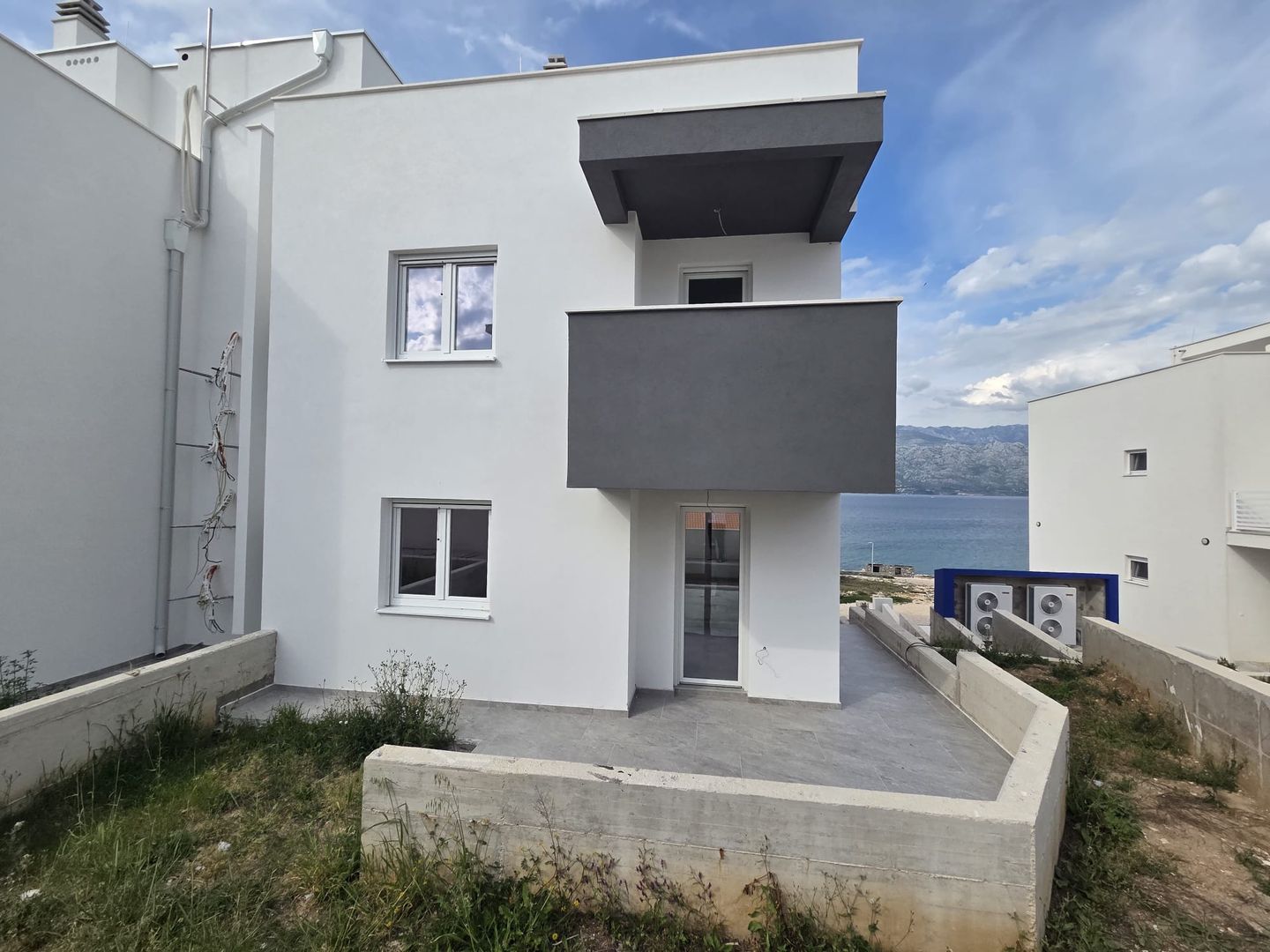 Facade of the residence facing the sea, with dark grey balconies and the Velebit channel behind